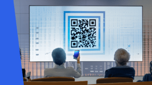 Gruppe von Personen, die ihre Smartphones nutzen, um einen QR-Code von einer Präsentation zu scannen, während das Ergebnis auf einer großen Leinwand dargestellt wird.